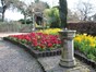 a cobbled footpath is lined with brightly coloured summer bedding plants and the parks sundial