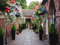 cobbled walkway lined with flower hanging baskets and brick arches either side