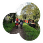 two people walking down a canal path with a canal boat to the right