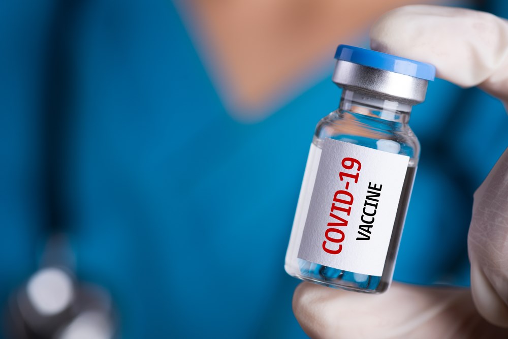 COVID-19 vaccine jar in hand of NHS worker