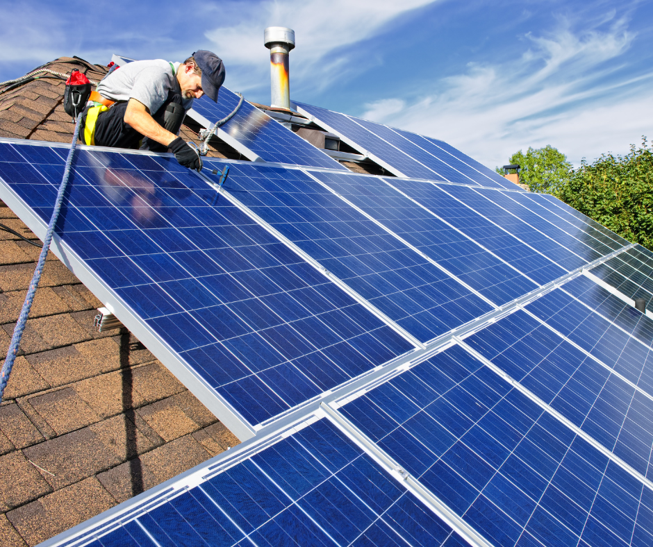 A worker installing solar panels on a house roof. 