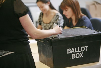 person putting a ballot paper in a ballot box