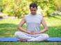 A man in a seated yoga pose in park