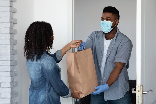 Man with face mask delivering food to woman