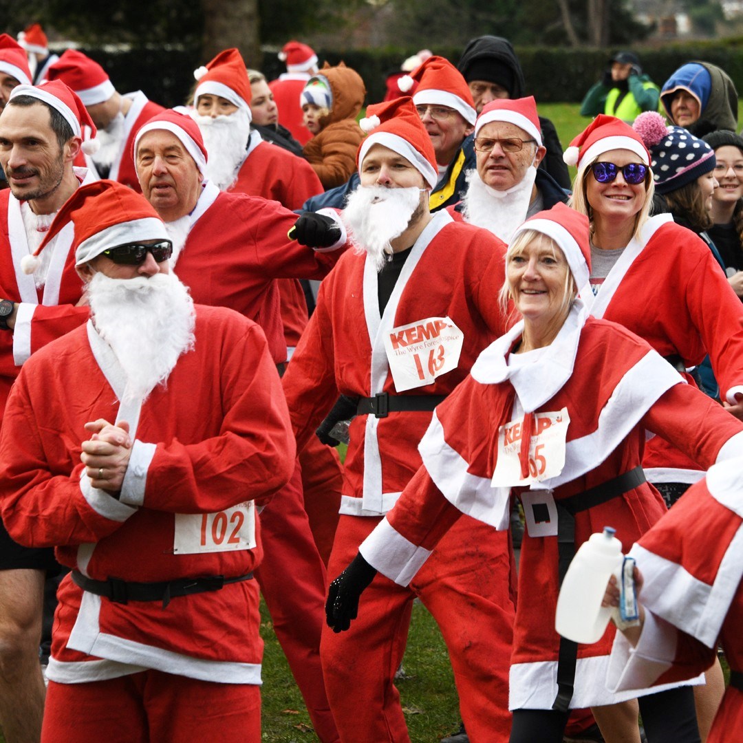 Group of men and women dressed in red santa outfits getting ready to race