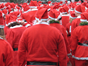 The backs of a crowd of people dressed in red santa outfits