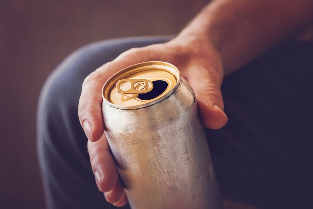 Person's hand holding a can of alcohol.