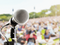 microphone in front of blurred images of people sat outside at music event