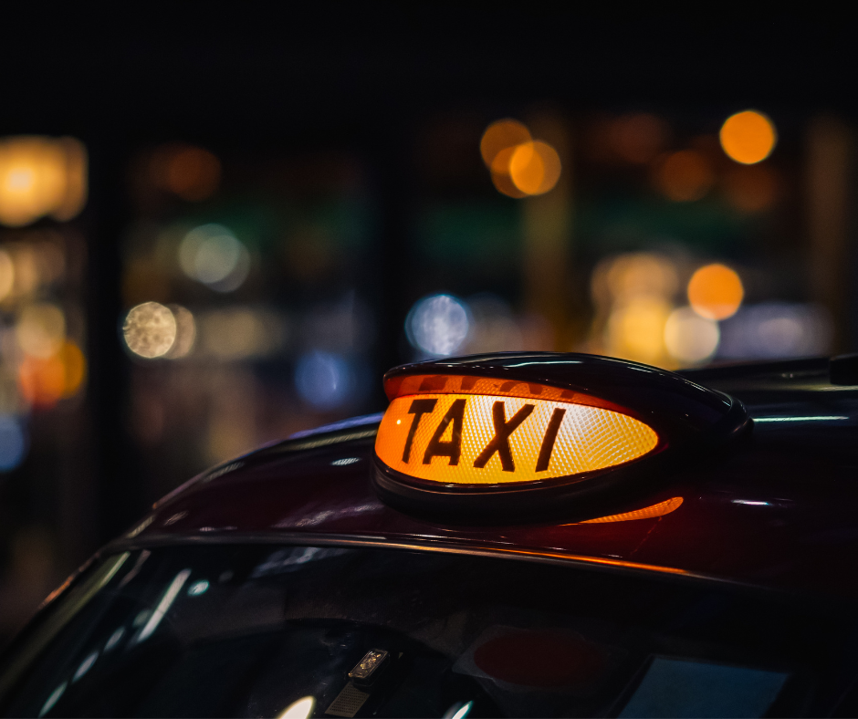 Yellow taxi light up sign on on top of a black hackney carriage 
