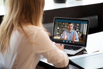 Woman on computer talking to man on virtual meeting