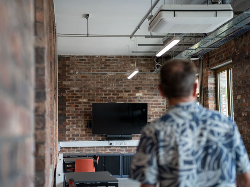 A person looking around a room with a TV and exposed brick walls