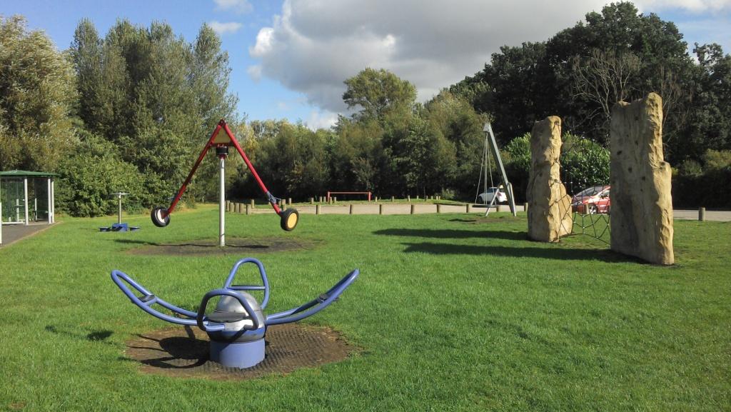 Older children's play area with climbing apparatus located on grassed area in public park.