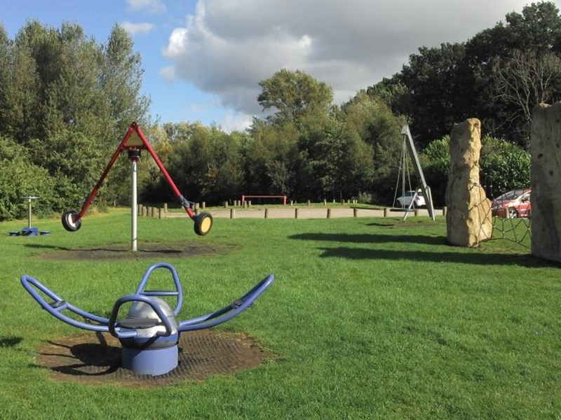Older children's play area with climbing apparatus located on grassed area in public park.