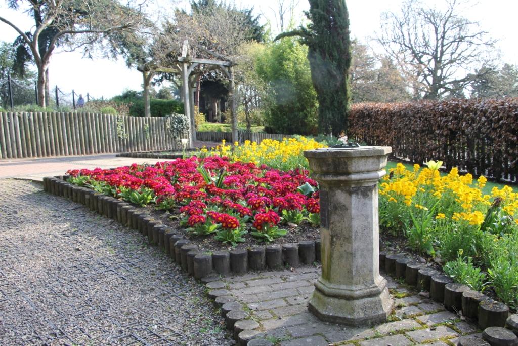 a cobbled footpath is lined with brightly coloured summer bedding plants and the parks sundial