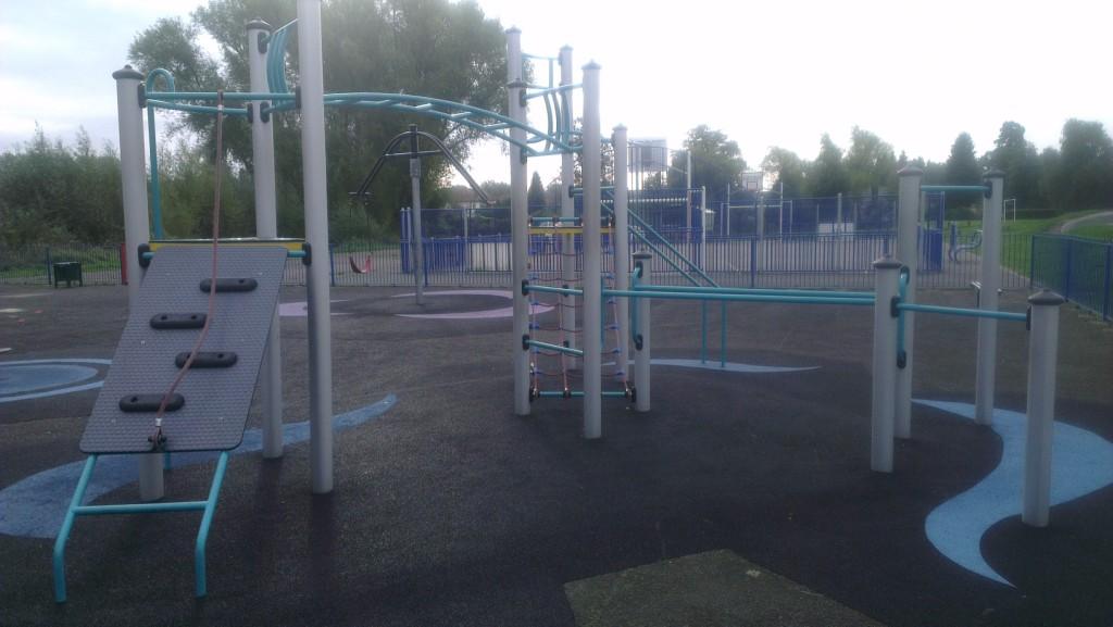 Children's climbing frame across multiple levels and stretching vastly across the play area on the soft surface floor covering. Located centrally in the public park.