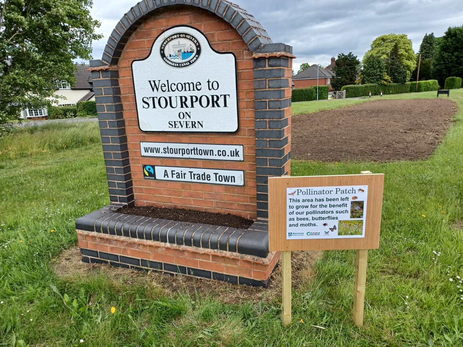 welcome to stourport on severn sign with small pollinator patch sign alongside, an area of freshly dug soil behind.