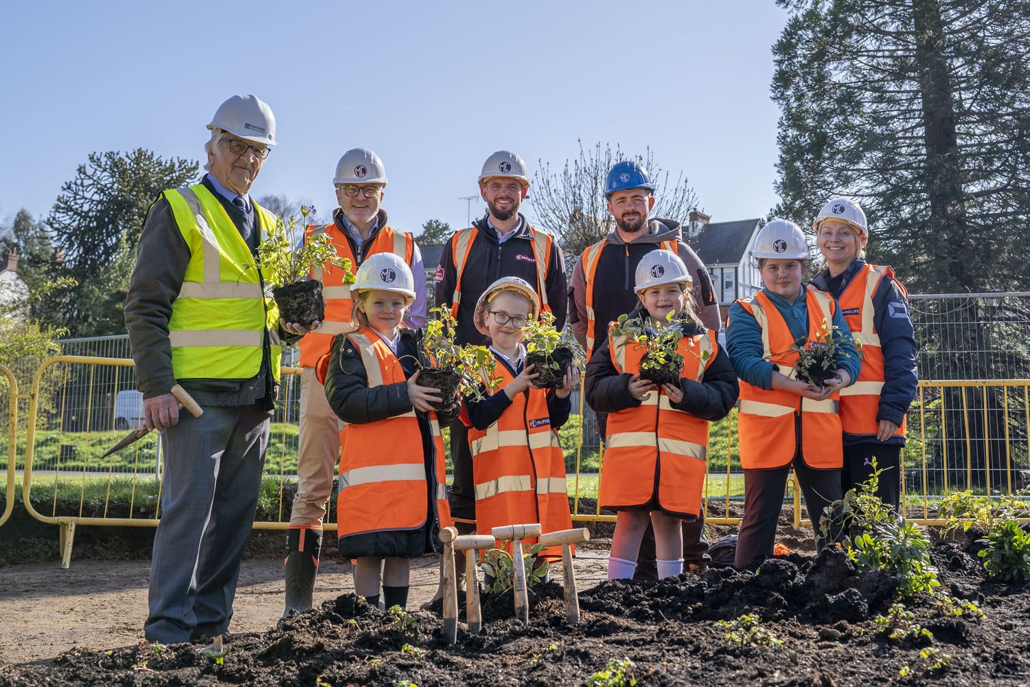 A group of people including adults and children wearing hard hard and high vis jackets