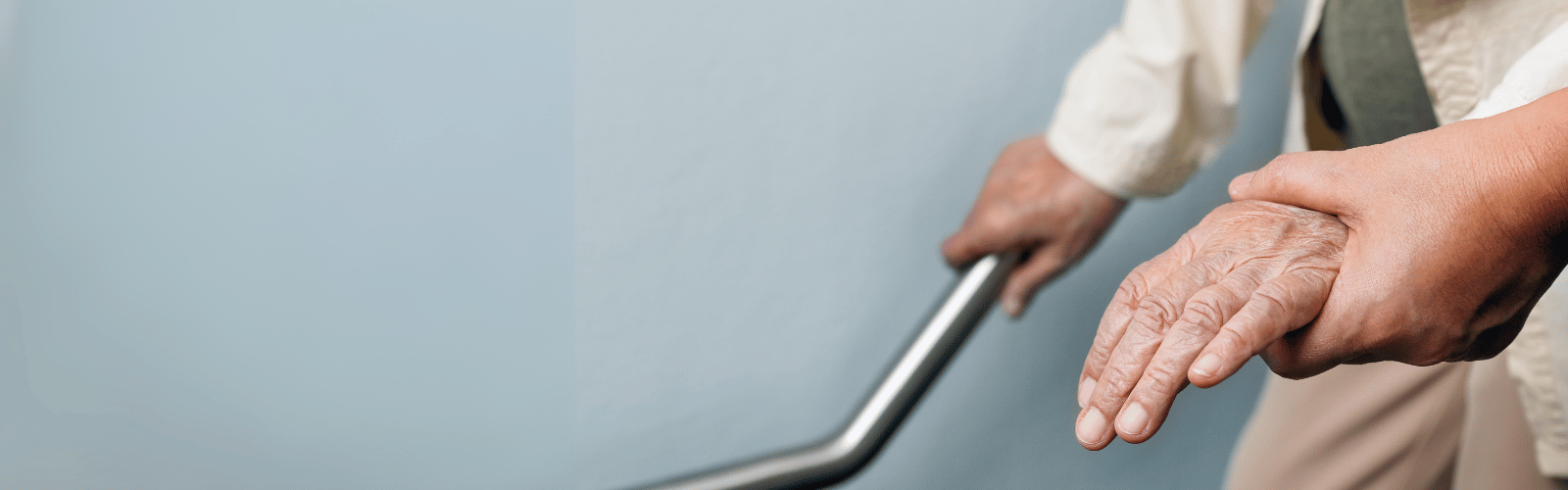 younger hand holding older hand, other older hand hold a railing