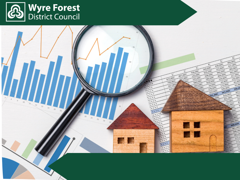 Wooden model houses and a magnifying glass on top of papers with graphs on