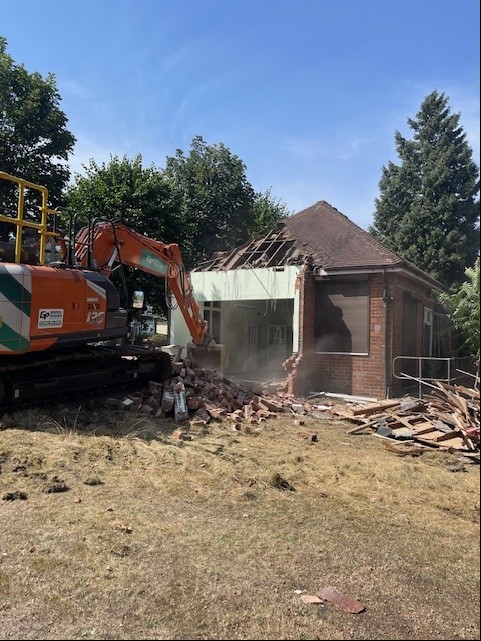 Digger knocking down a single storey building