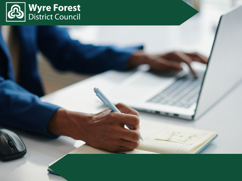 Close up of some one writing notes with one hand and typing on a laptop with other