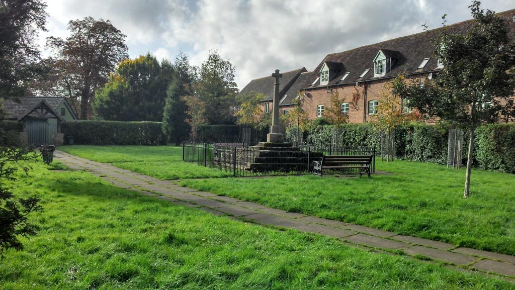 distant view of memorial surrounded by railings. Georgian building surround the garden of rest