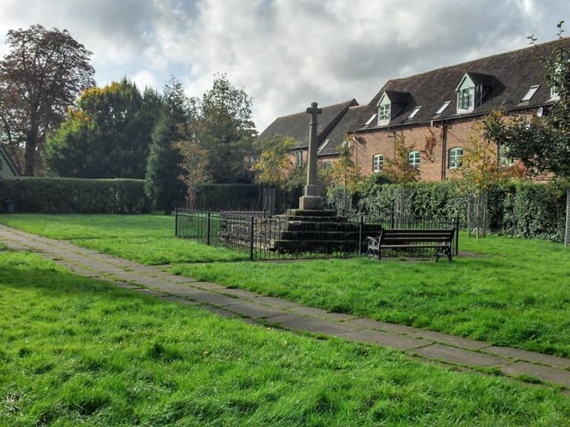 distant view of memorial surrounded by railings. Georgian building surround the garden of rest