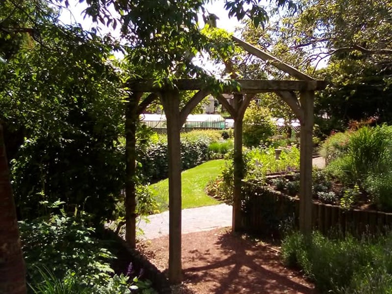 Wooden frame over footpath surrounded by mature trees