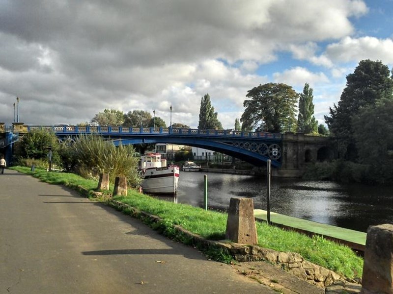 A footpath follows the winding River Severn through the Georgian town of Stourport-on-Severn, with a view of the river to the left and the river bridge in the distance.