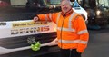 refuse worker stood by bin lorry with green bow on front to support mental health awareness
