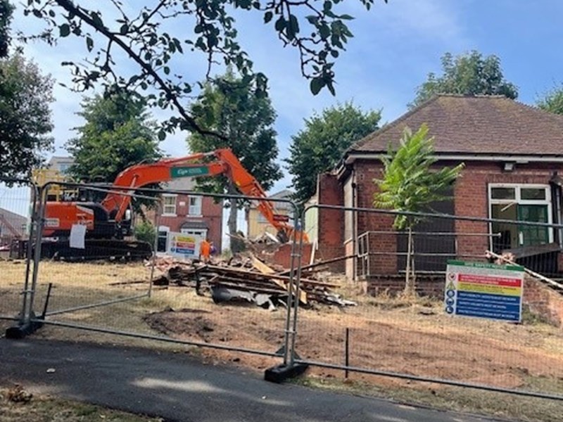 Digger in front of single story building