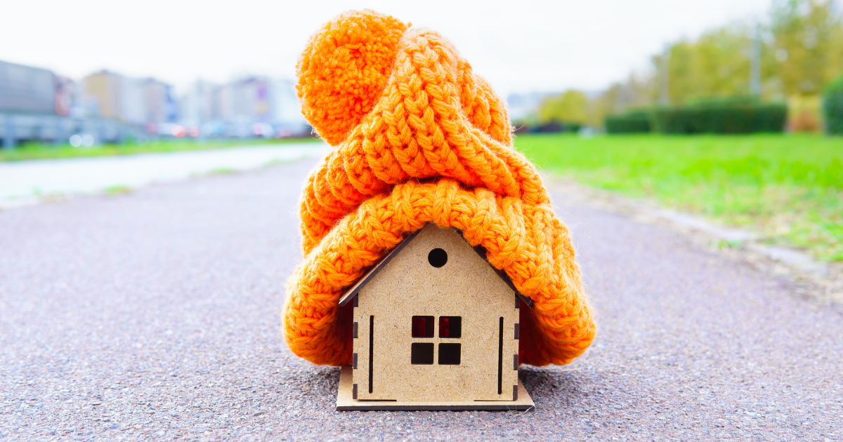A small model house with an orange woolly hat on. 