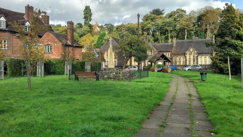 Small area of open green space with benches and footpath running through the centre. Surrounded by old Georgian houses, church and buildings