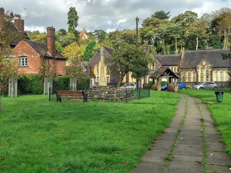 Small area of open green space with benches and footpath running through the centre. Surrounded by old Georgian houses, church and buildings