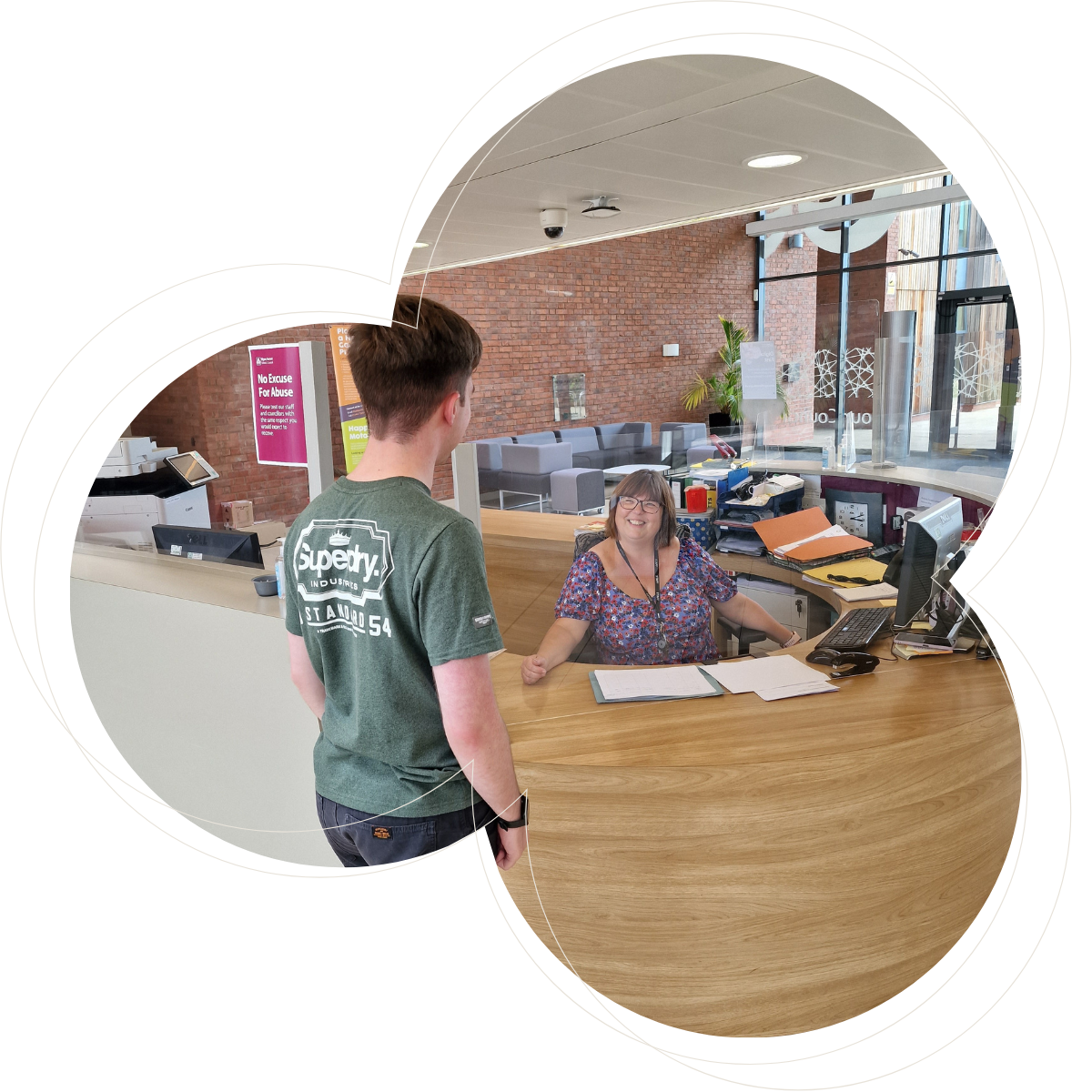 a male stood at a reception desk with a female receptionist smiling back