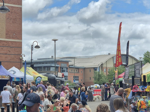 Lots of people sitting on benches and looking at street foot stalls