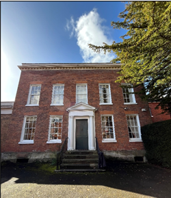 a three-story brick building with white-framed windows and a central entrance featuring a small portico with columns.