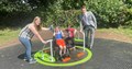 child in wheelchair with friend and mother, with a local male councillor