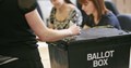 person putting a ballot paper in a ballot box