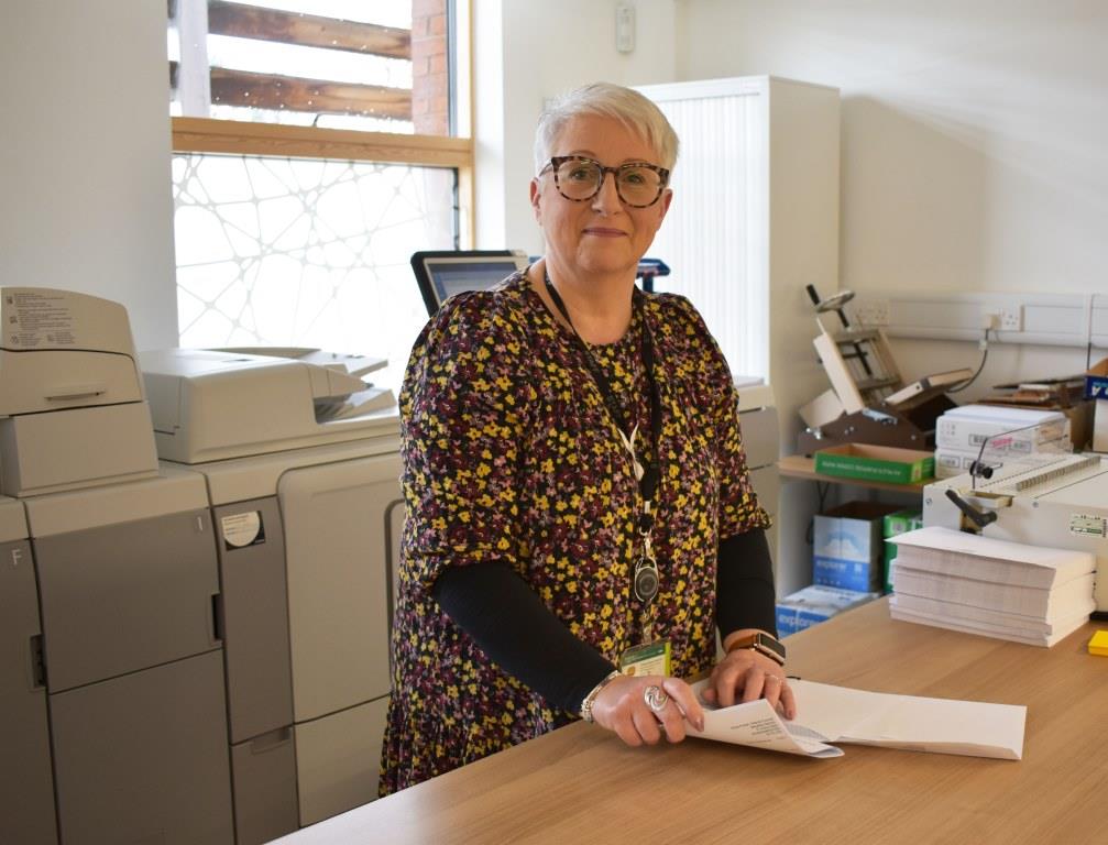 smiling woman stood at a desk