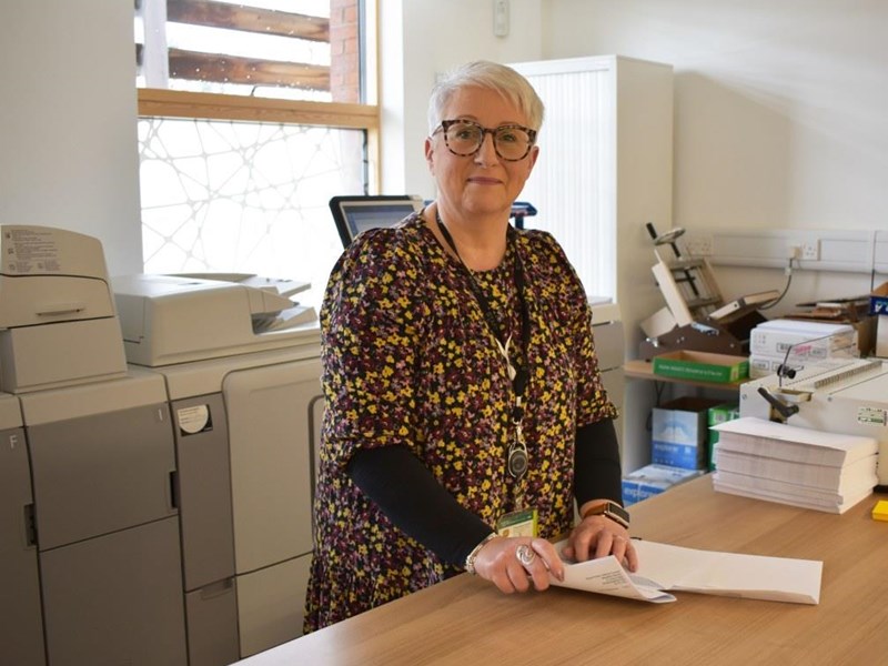 smiling woman stood at a desk