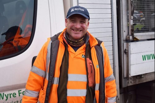 smiling man in high vis jacket in front of white lorry