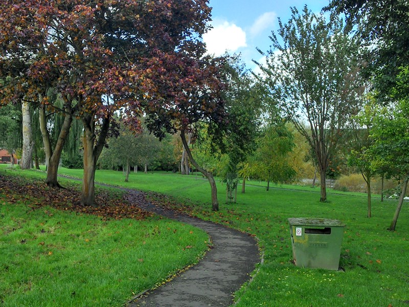 grassed area with centralised footpath with mature trees dotted on either side to provide shade from the hot summer sun or April showers of rain.