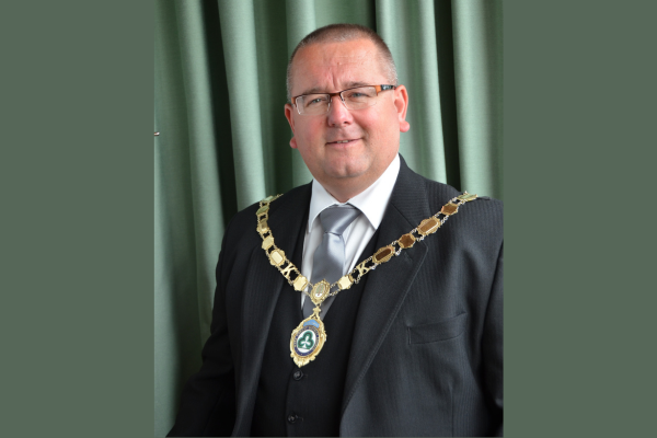A middle aged man in a suit wearing a chain of office