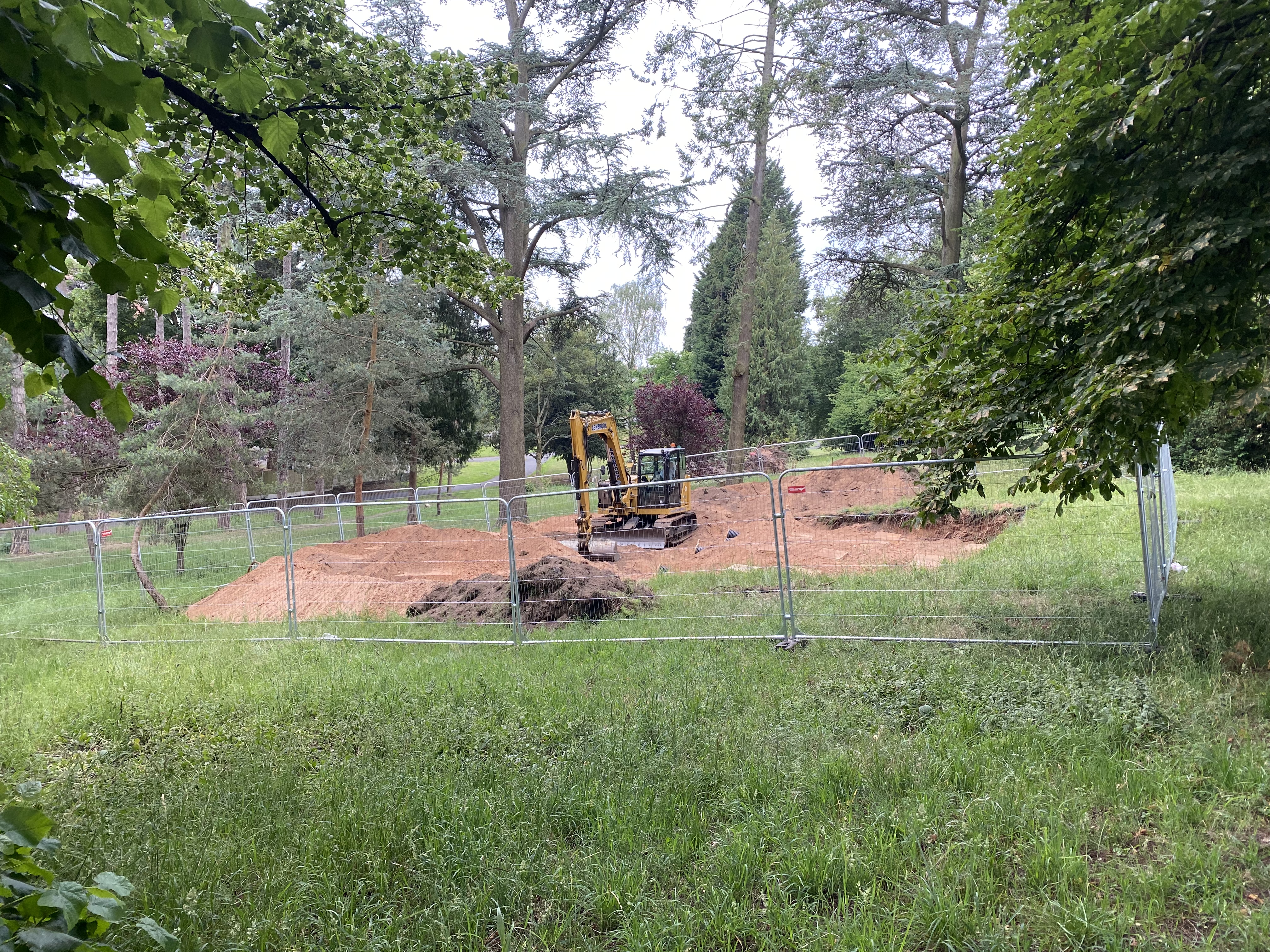 A digger in a park surrounded by upturned earth