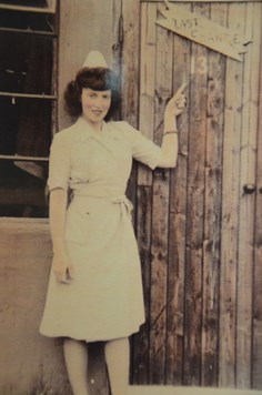faded colour photo of uniformed nurse pointing at old wooden door
