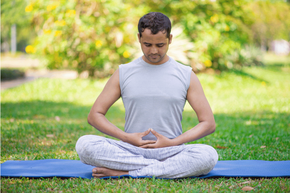 A man in a seated yoga pose in park