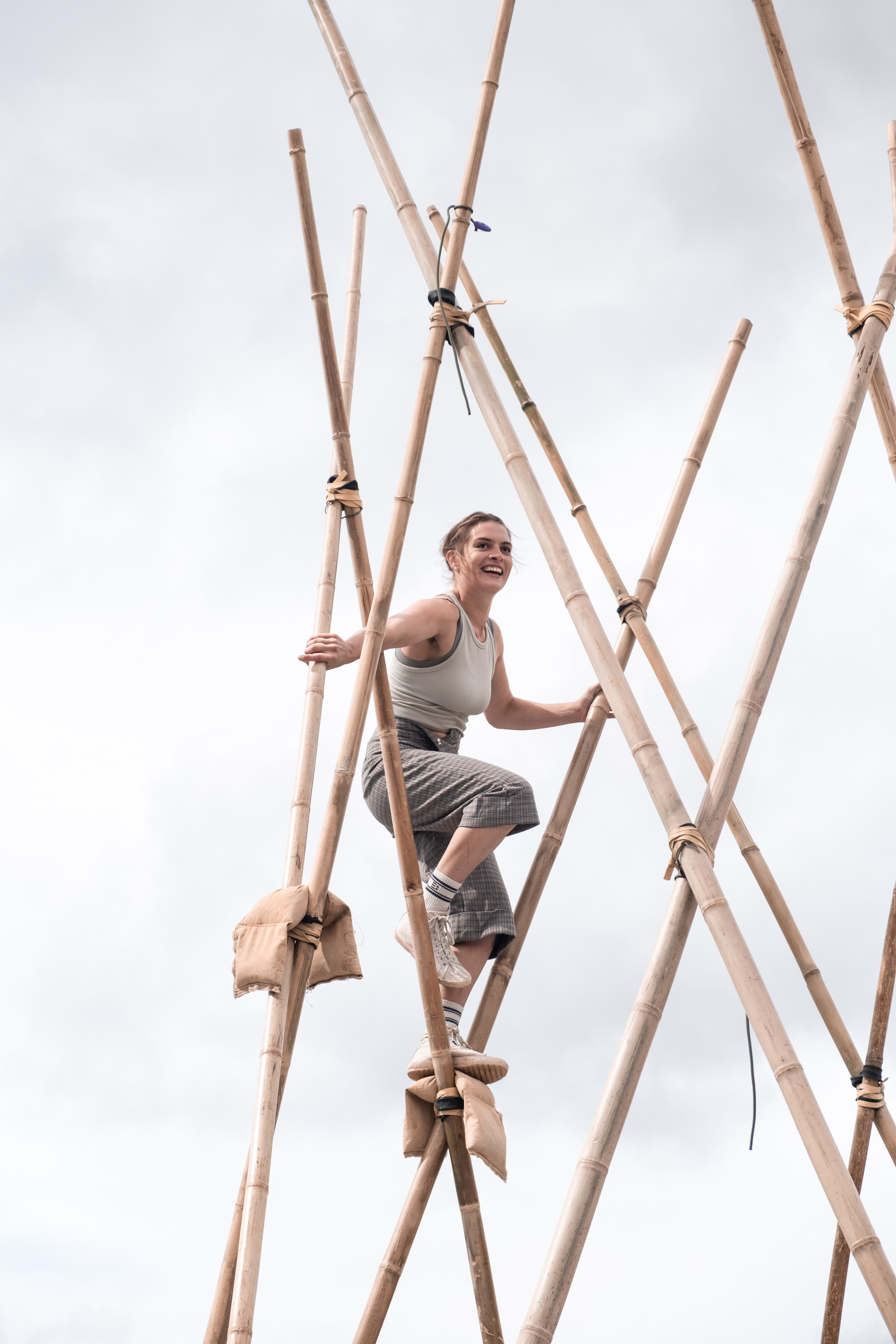 Photo of an acrobat balancing up high on a framework of bamboo canes