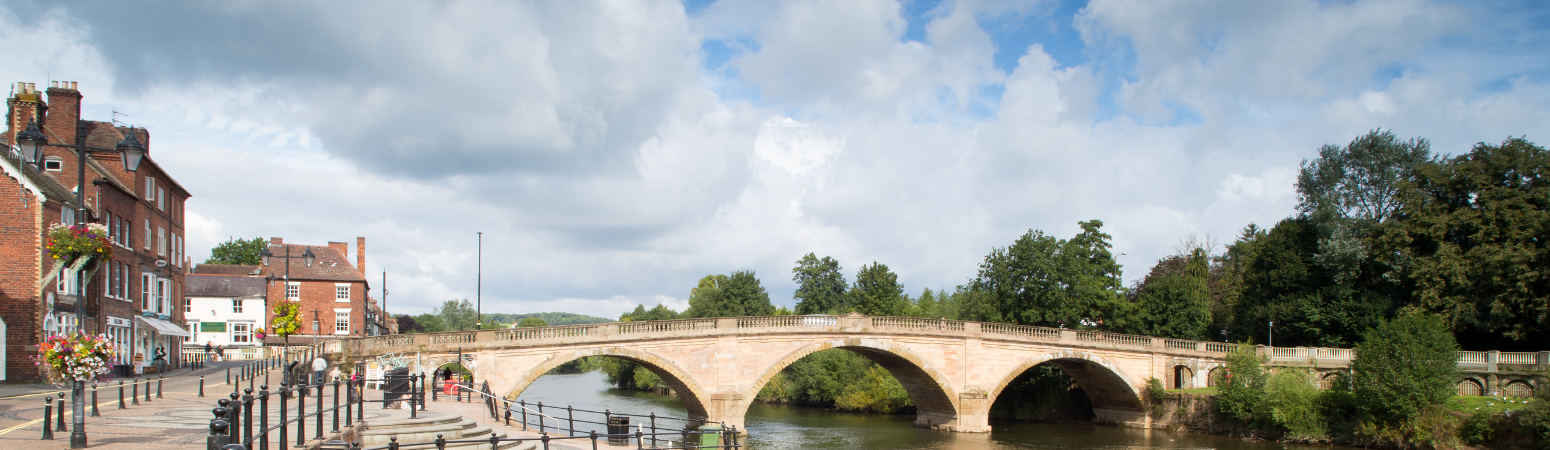 Scenic view of pale brick bridge over river, blue sky and light cloud above