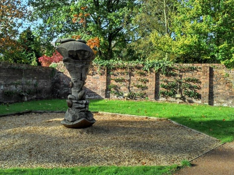 An area of the public gardens where a wooden apple core sculpture has been crafted from an old tree trunk.